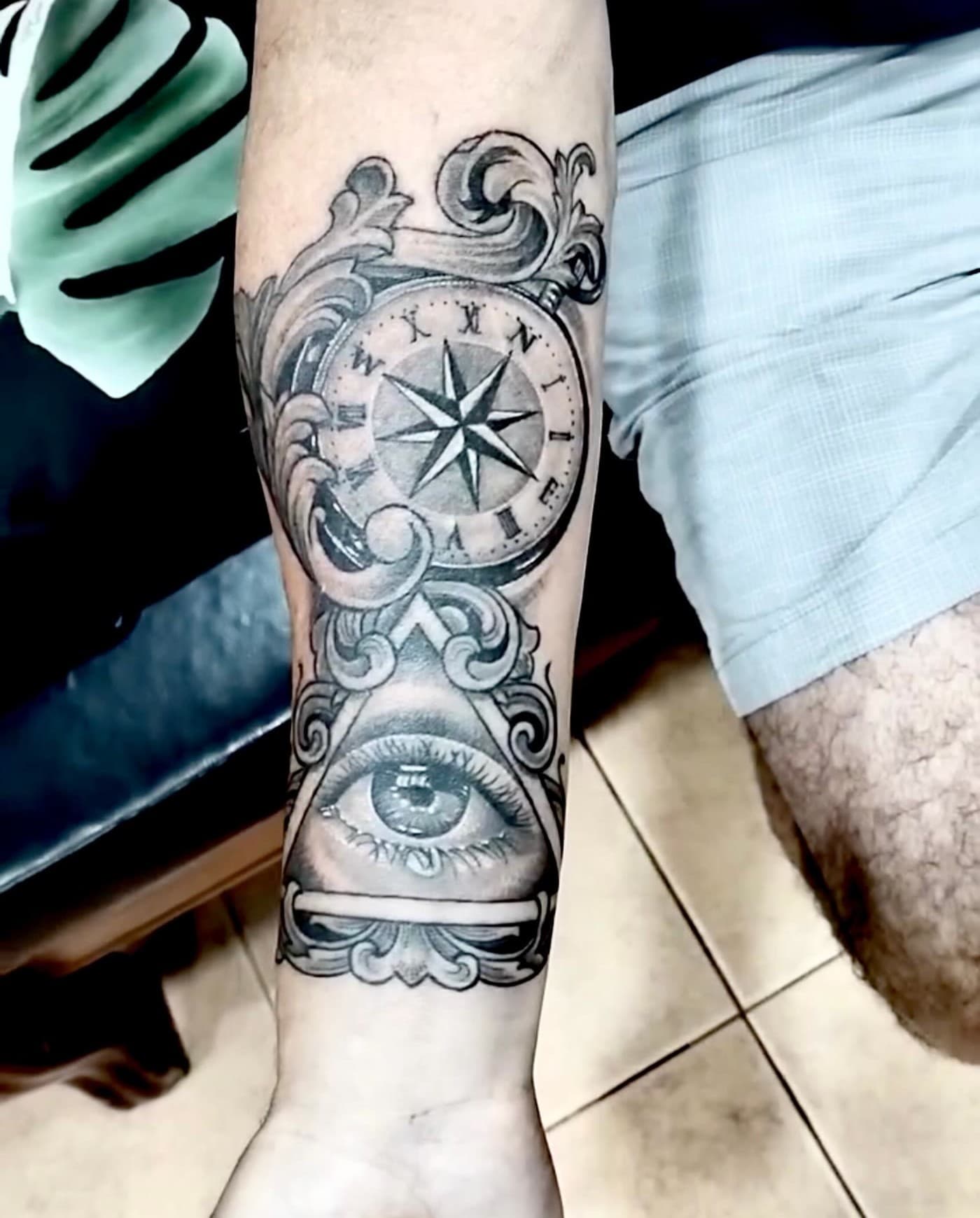 Compass and eye tattoo on the forearm