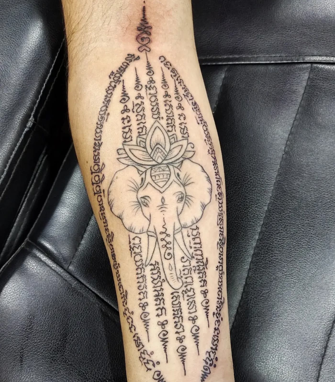 Elephant yantra framed in Khom script and lotus on a forearm